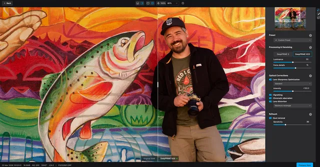 A smiling man in a cap holds a camera and stands beside a colorful mural of a leaping fish, with a photo editing program open showing adjustments on the…